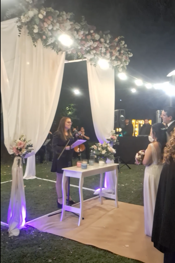 Ceremonia de boda de noche, bajo un arco de flores y luces